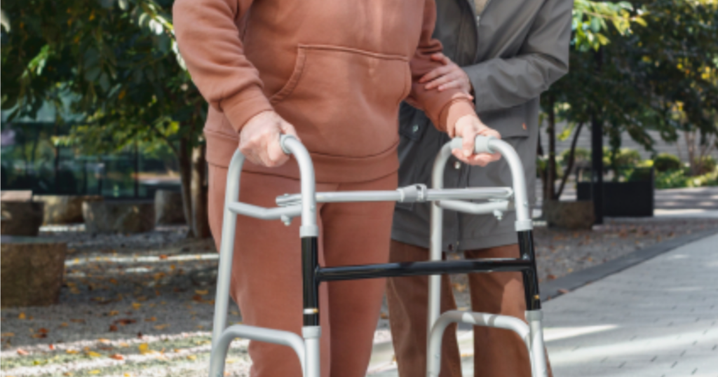 外で介助を受けながら歩行訓練をする