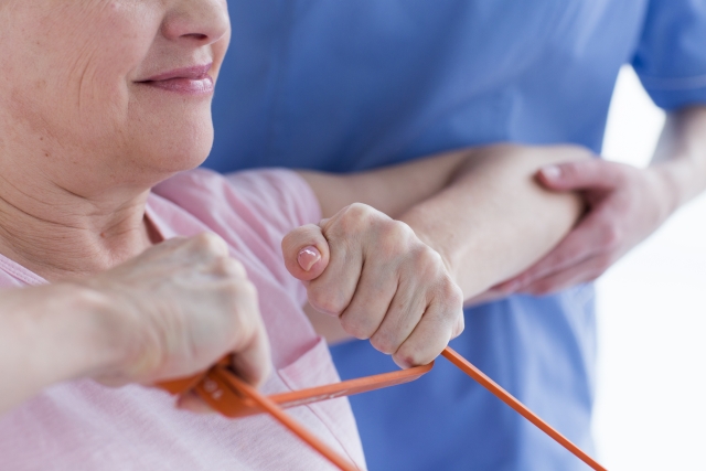 ゴムチューブを使用してリハビリを行っている場面