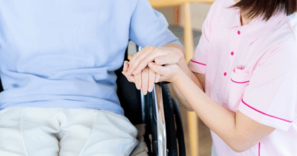 スタッフが車椅子に乗っている利用者の手に自分の手を添えている