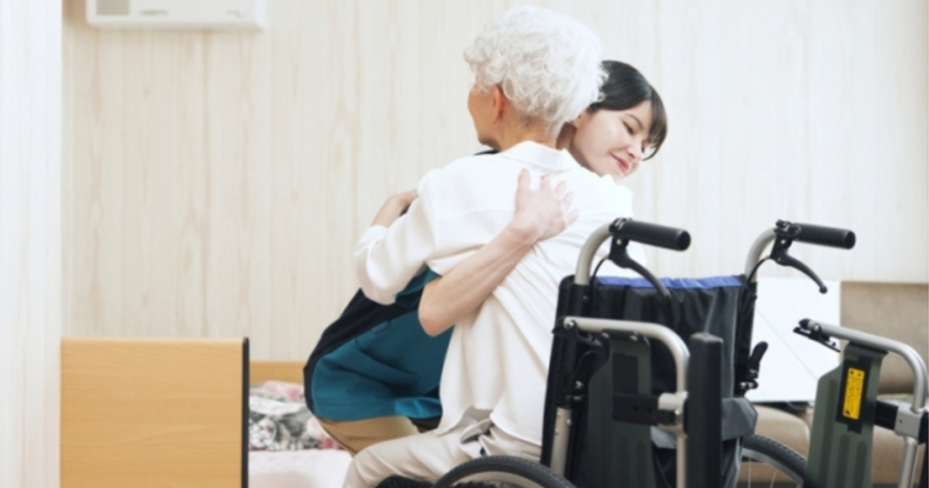 介護スタッフが車椅子から利用者を移乗させようとしている