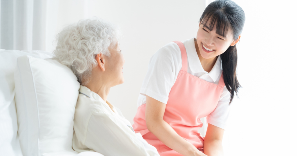 介護スタッフがベッドにいる利用者と会話している