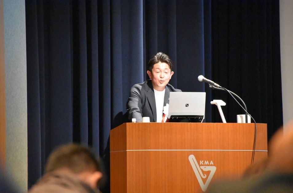 演台に立ち、パソコンの資料を確認しながら熱心に講演を行う福井さん
