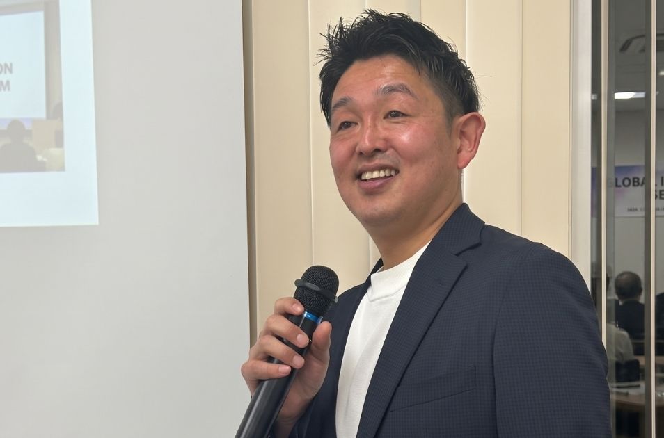 マイクを手に持ち、参加者に向けて笑顔で語りかける福井さん