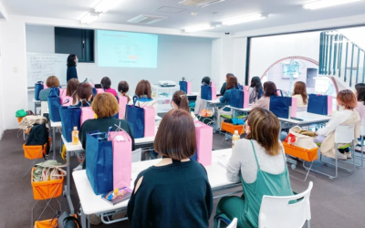 介護美容研究所の講義風景。プロジェクターを使った講師の説明を、多くの女性受講生が熱心に聞いている教室の様子。