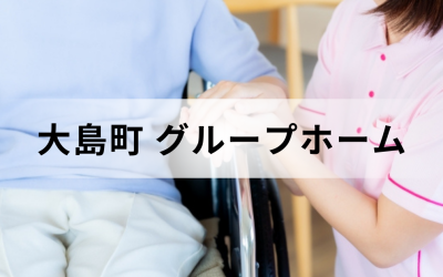 介護コラム：大島町のグループホーム事情。ピンクのユニフォームを着た介護スタッフが、車椅子に乗った高齢者の手を優しく握っている安心感のあるイメージ。