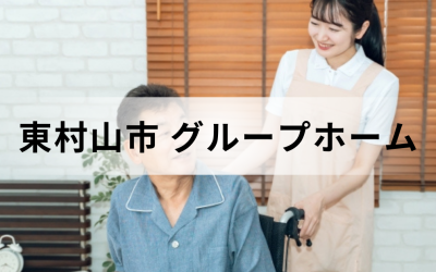 東京都東村山市のグループホーム（認知症対応型共同生活介護）。車椅子のシニア男性に笑顔で寄り添う女性介護スタッフのイメージ。