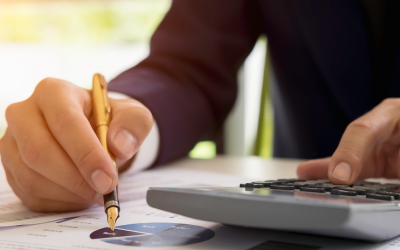 介護費用の計算をする様子：デスクで電卓を叩き、書類にペンを走らせるスーツ姿の人物の手元。ファイナンシャルプランナーや相談窓口のイメージ。