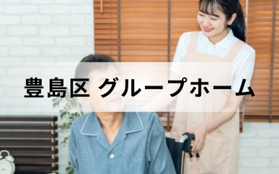東京都豊島区のグループホーム。ベージュのエプロンを着た笑顔の介護スタッフと、車椅子に乗った高齢男性の温かいイメージ。
