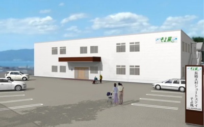 長崎県初進出となる「長崎大村ショートステイそよ風」の外観完成予想CG。白い建物と広い駐車場があり、奥には海が見えるロケーション。