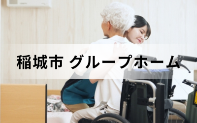 稲城市のグループホーム。車椅子の横で、シニア女性を笑顔で優しく抱きしめる女性介護スタッフのイメージ。