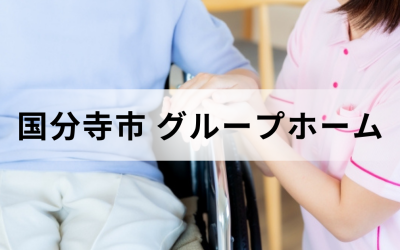 東京都国分寺市のグループホーム（認知症対応型共同生活介護）。車椅子の高齢者の手を優しく握る女性介護スタッフのイメージ。