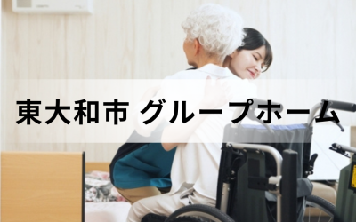 東京都東大和市のグループホーム。車椅子の傍らで、高齢者を笑顔で優しく抱きしめる介護スタッフの愛情あふれるイメージ。