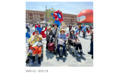公式キャラクターのミャクミャクを背景に、車椅子や歩行器を利用して2025大阪・関西万博を楽しむ5人のシニア女性たちの笑顔の写真。