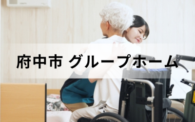 東京都府中市のグループホーム（認知症対応型共同生活介護）。ベッドに座る高齢女性を笑顔で優しくハグする女性介護スタッフのイメージ。