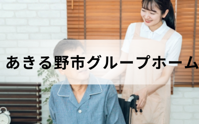 介護コラム：あきる野市のグループホーム事情。ベージュのエプロンを着た笑顔の介護スタッフと、車椅子に乗った高齢男性の温かいイメージ。
